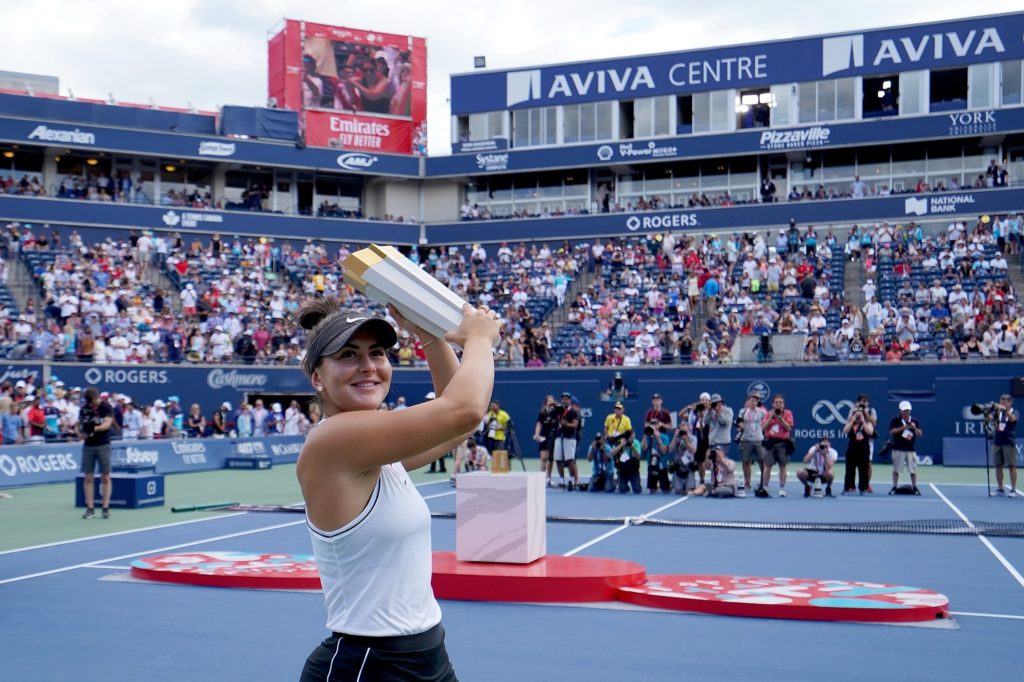 Andreescu smiles and lifts her trophy from the National Bank Open in Toronto for the crowd
