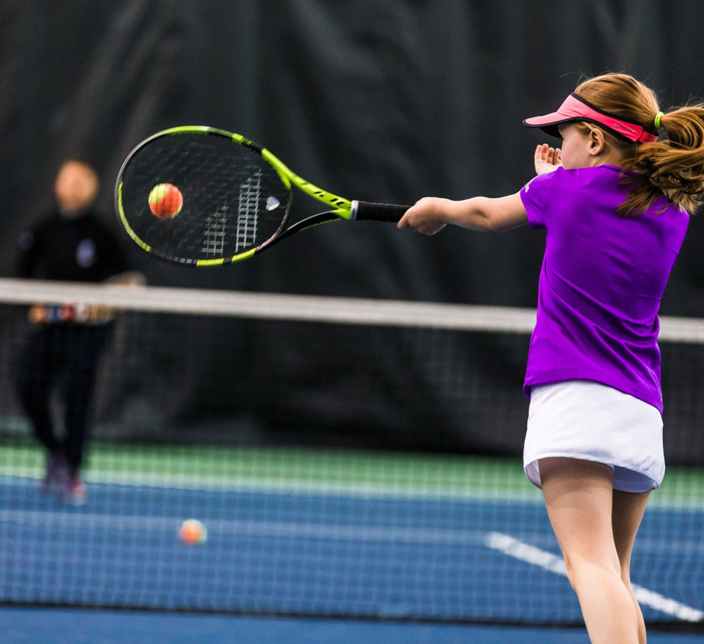 Young girl serving tennis ball