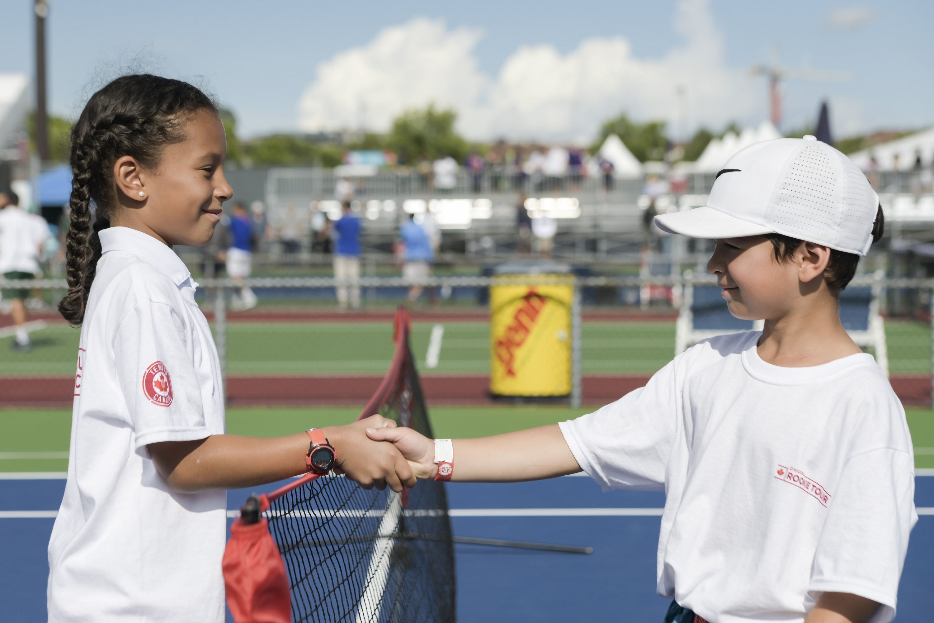 Girl and boy shake hands on tennis court