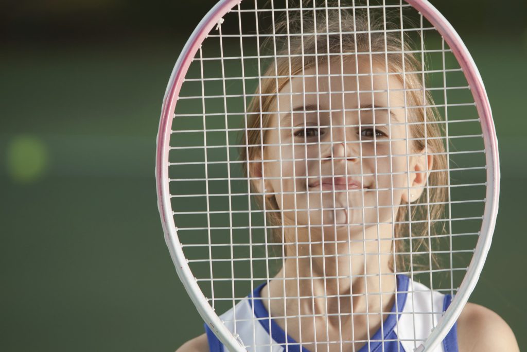Young girl behind tennis racquet
