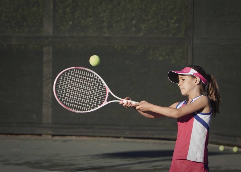 tennis playing girl hits ball with a racket