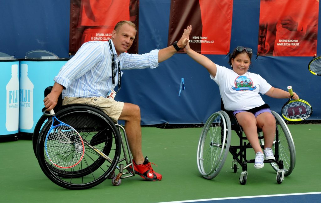 kei schrameyer hi-fives a wheelchair tennis player