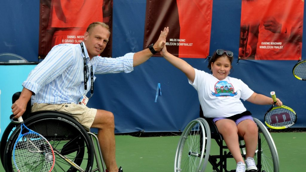 kei schrameyer hi-fives a wheelchair tennis player