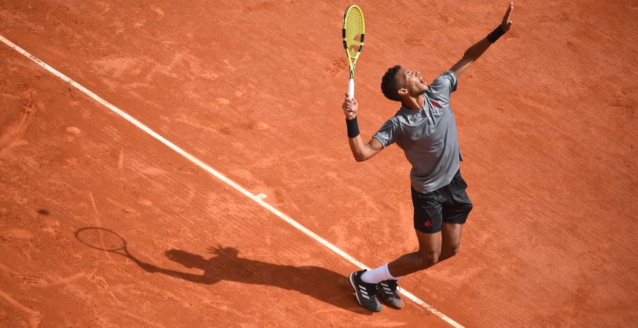 Félix prepares to hit a serve on a clay court