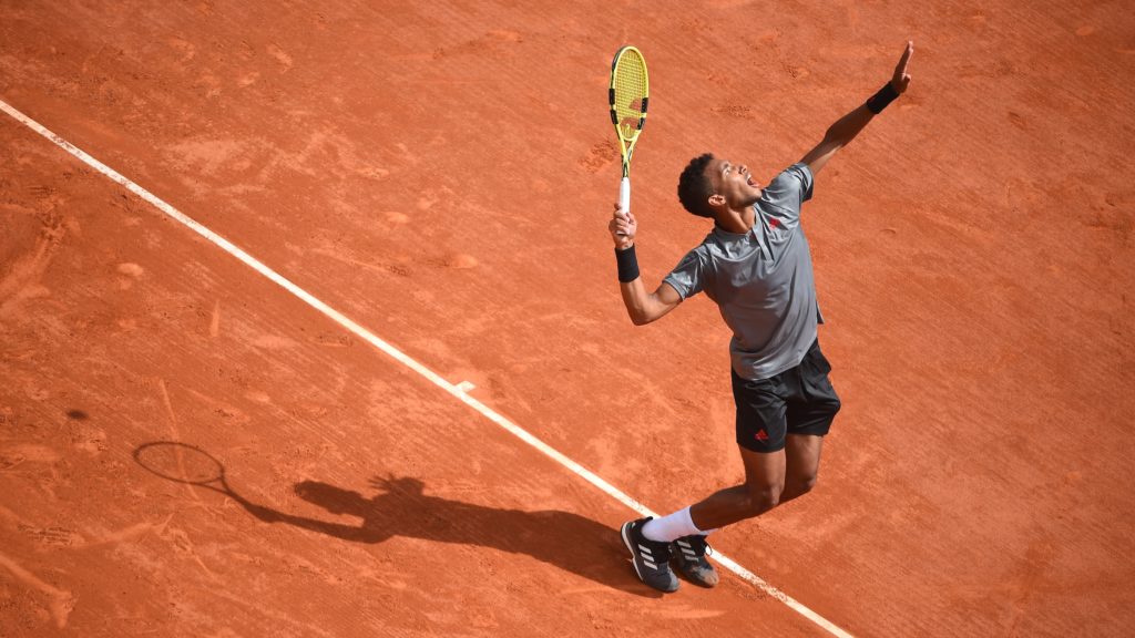 Félix prepares to hit a serve on a clay court