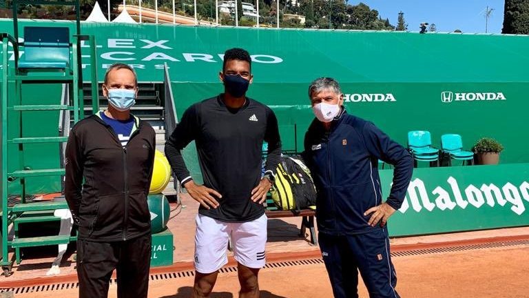 Felix stands with toni nadal on a clay court