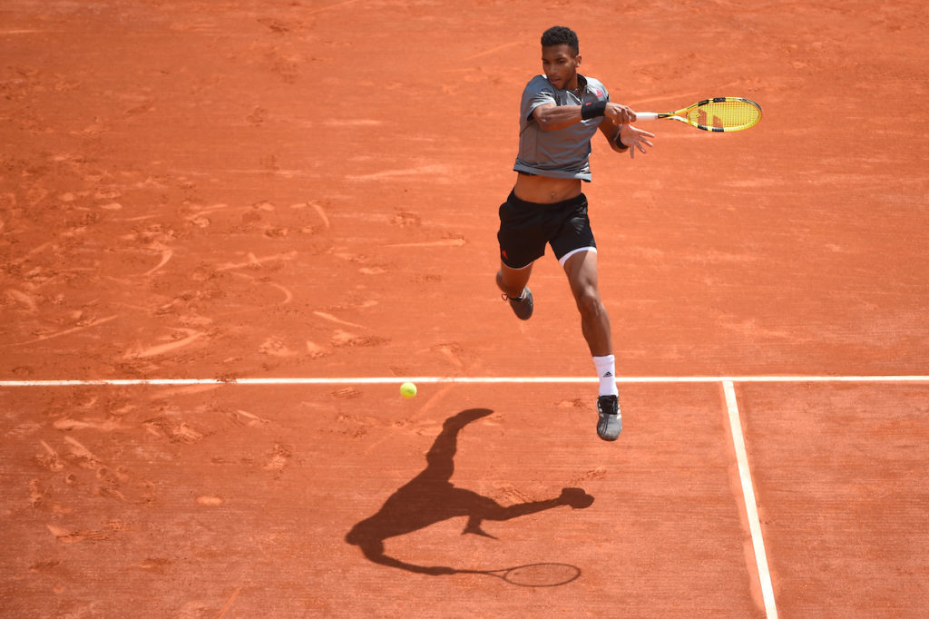 Felix hits a forehand on a clay court