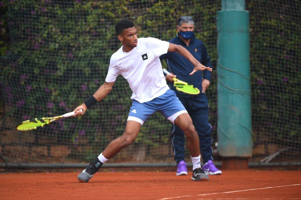 Felix Auger-Aliassime hits a forehand during practice while Toni Nadal watches