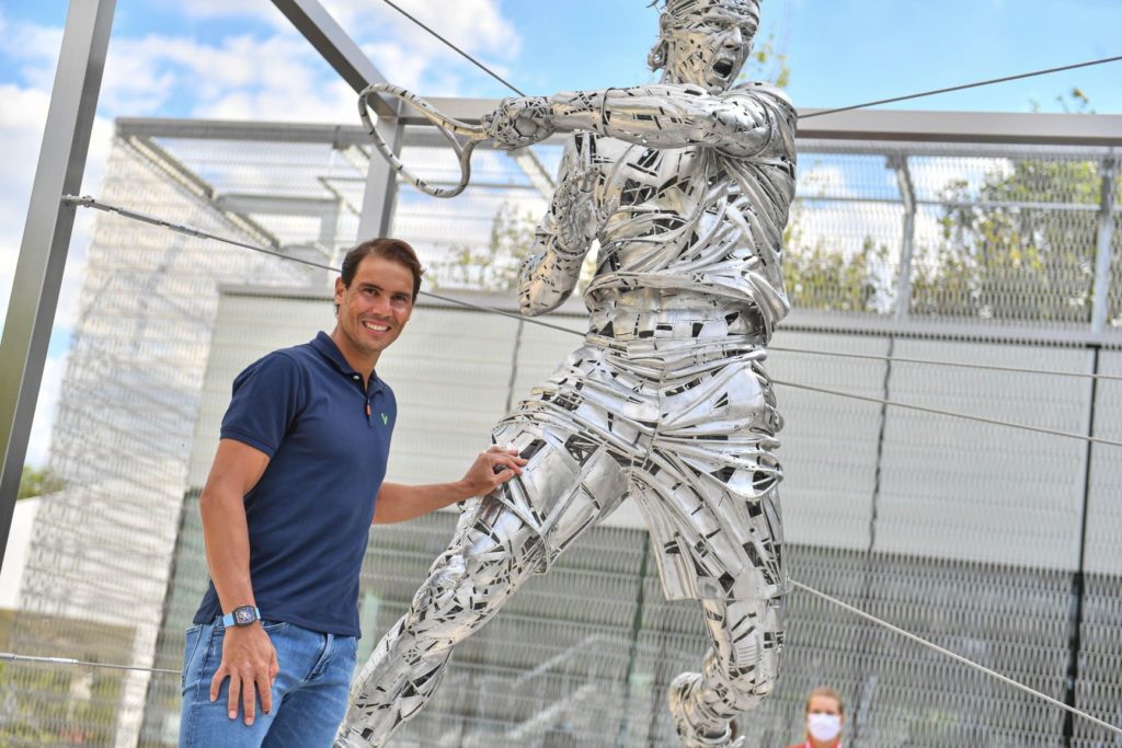 Rafael Nadal stands next to his statue at Roland Garros