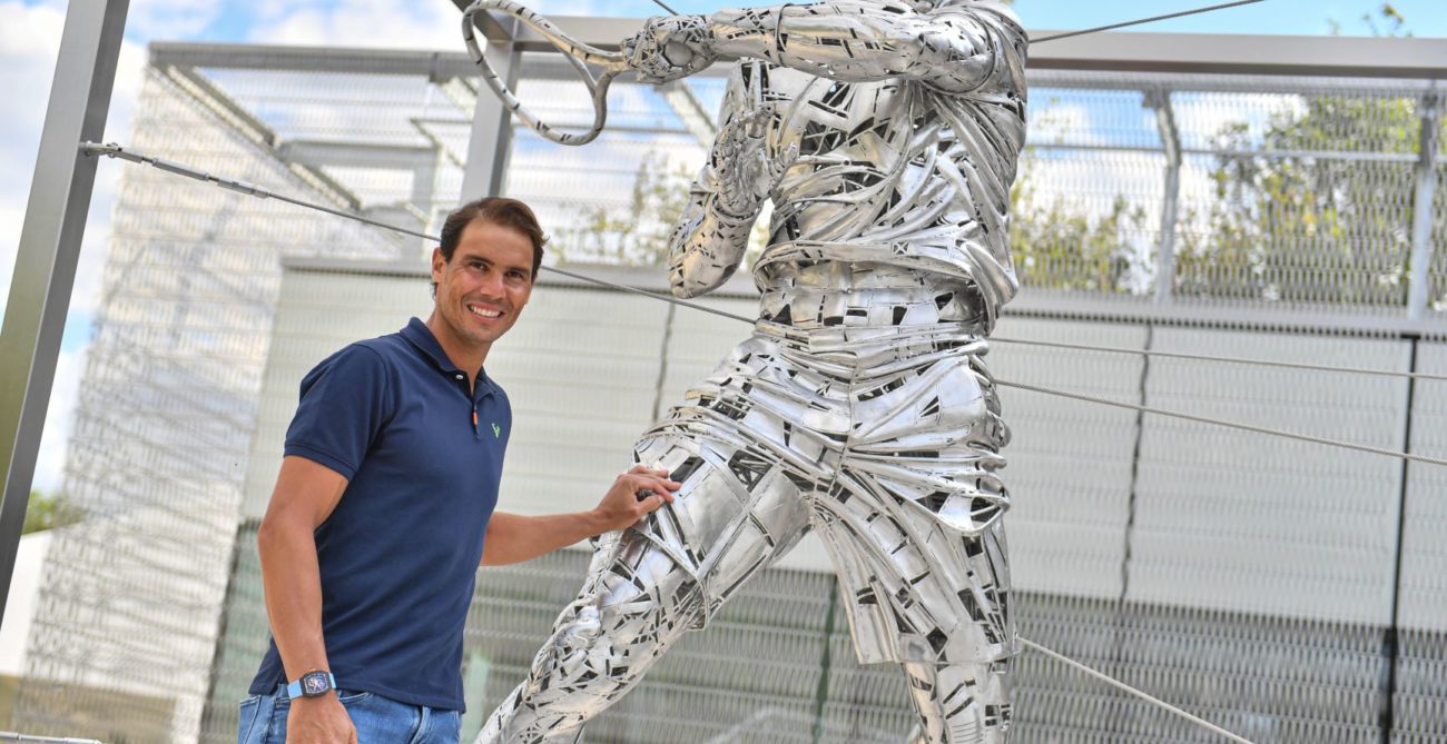 Rafael Nadal stands next to his statue at Roland Garros