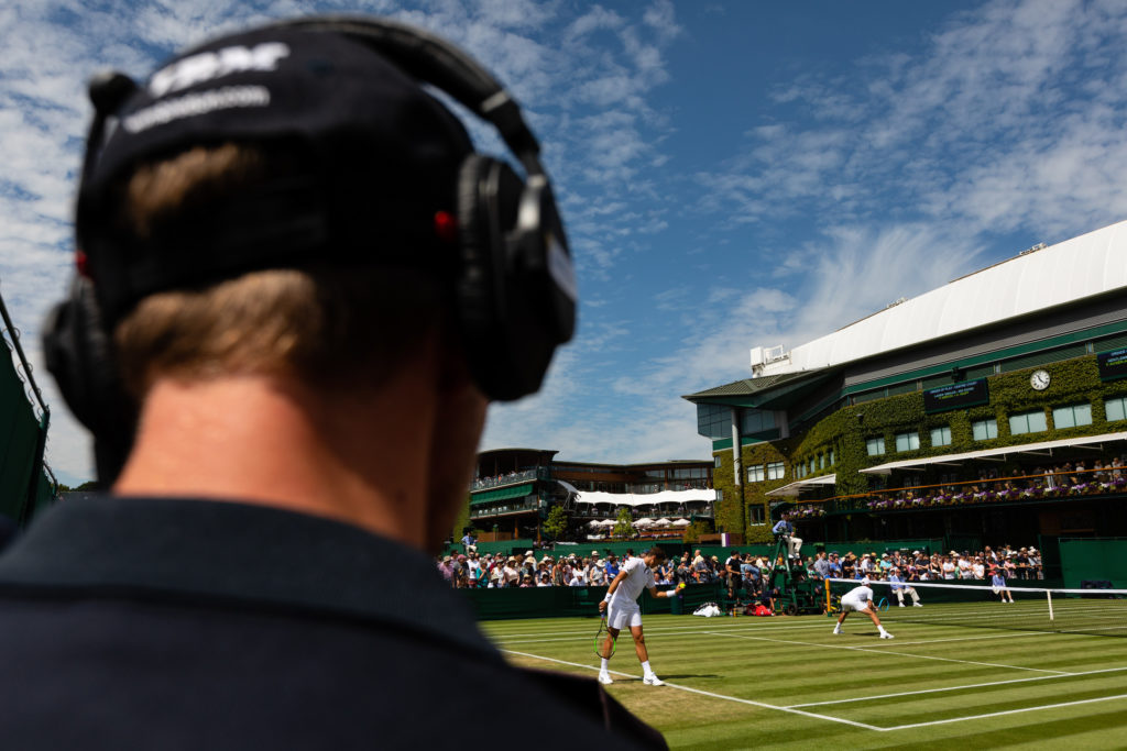 Person wearing a headset on an adjacent court at Wimbledon