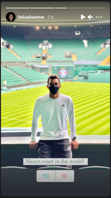Félix Auger Ailassime stands in front of Centre Court Wimbledon wearing a mask