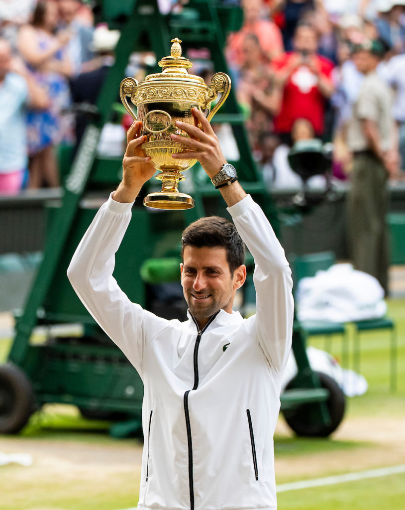 Novak Djokovic lifts the wimbledon trophy on court
