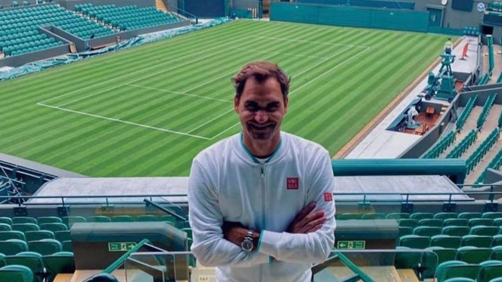 Roger Federer standing in front of the Centre Court at Wimbledon and smiling to the camera