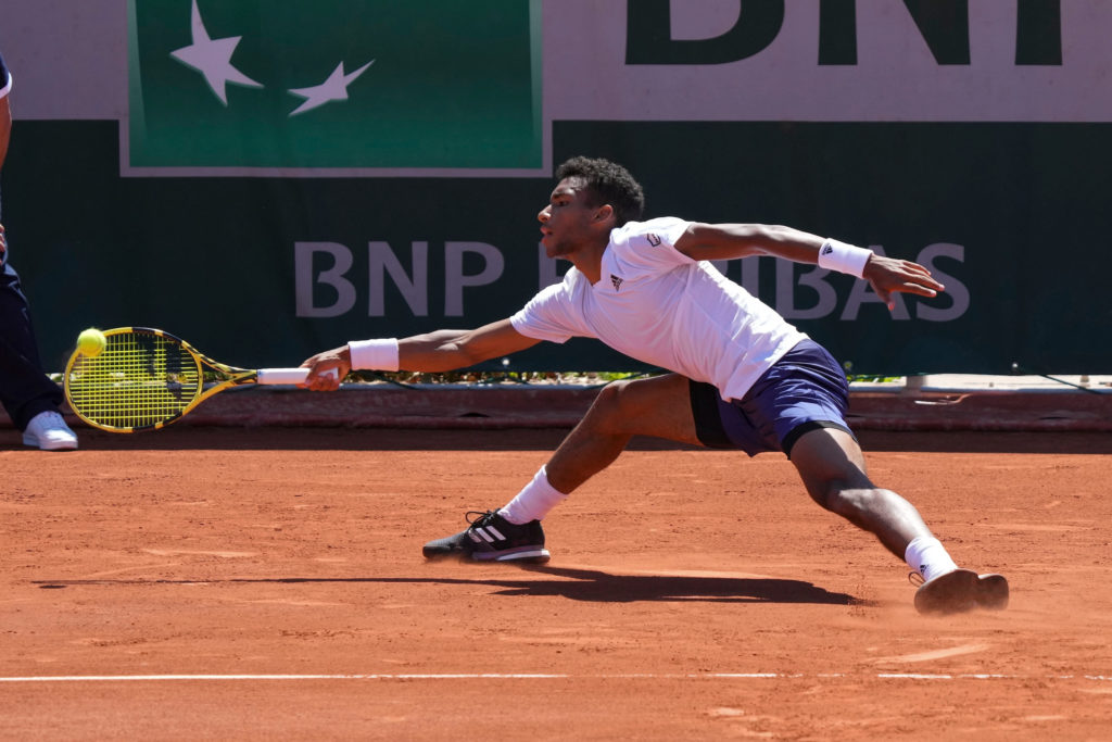 Felix Auger-Aliassime stretches to reach a ball on his forehand at Roland Garros