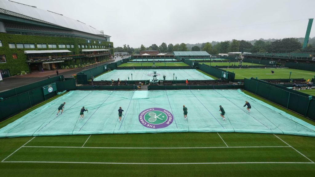 Wimbledon staff cover the courts to protect the grass from the rain