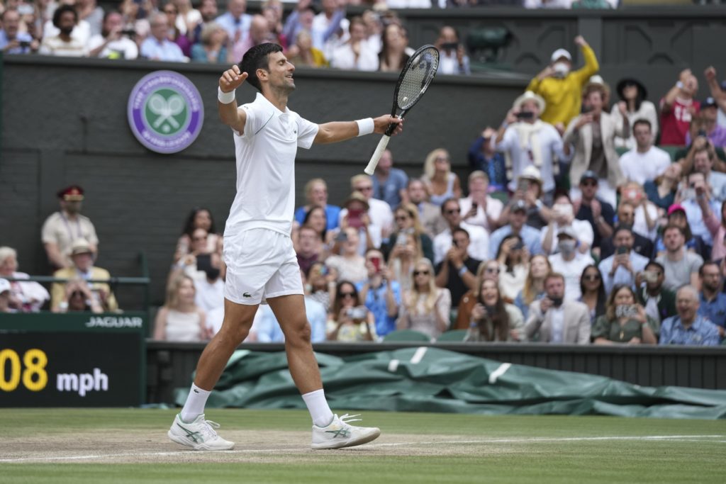Novak Djokovic walks with his arms open on Centre Court Wimbledon in relief after winning the tournament