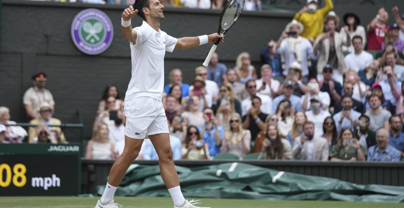 Novak Djokovic walks with his arms open on Centre Court Wimbledon in relief after winning the tournament