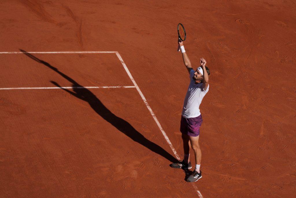 Stefanos Tsitsipas celebrates a win with his arms up in the air