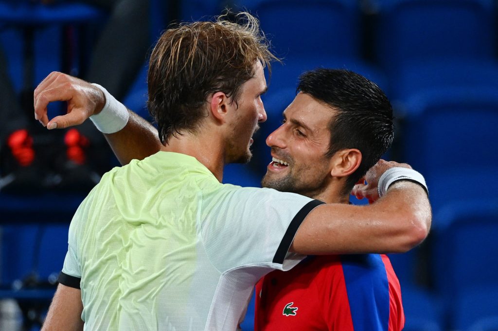 Alexander Zverev and Novak Djokovic embrace at the net