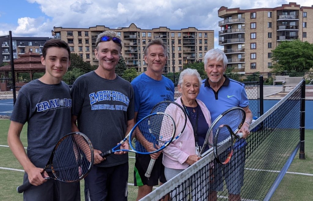 A family posing for a photo on a tennis court