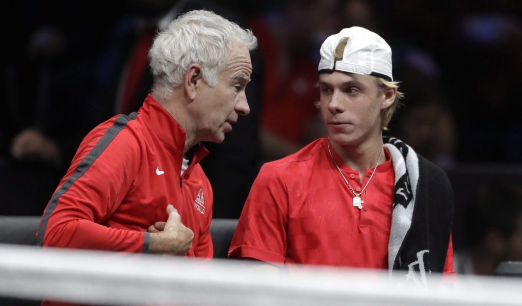 John McEnroe (left) leans in and talks to Denis Shapovalov