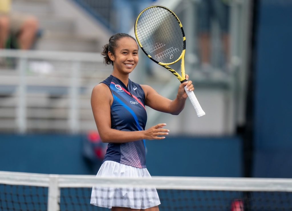 Leylah Fernandez smiles and raises her racket.