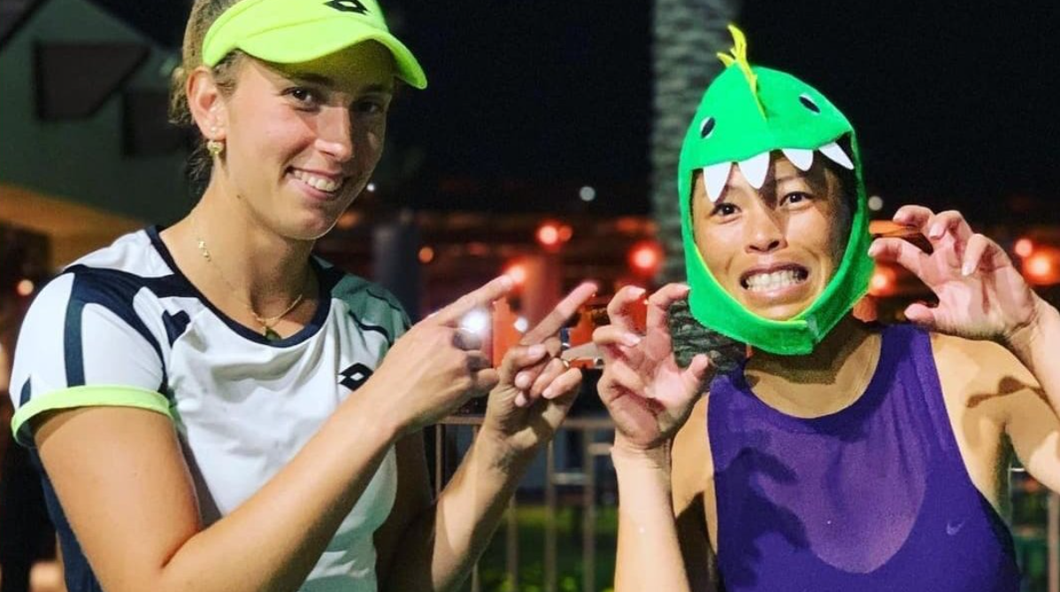 Elise Mertens (left) points at Su-Wei Hsieh who is wearing a dragon cap and growling.
