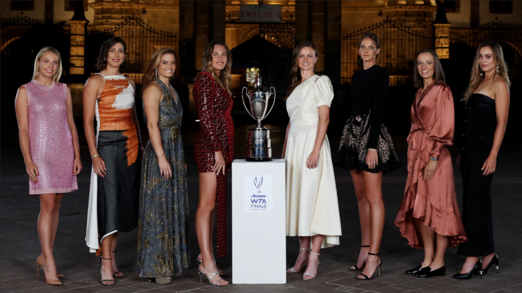 The WTA Finalists stand in a line with the trophy in the middle.