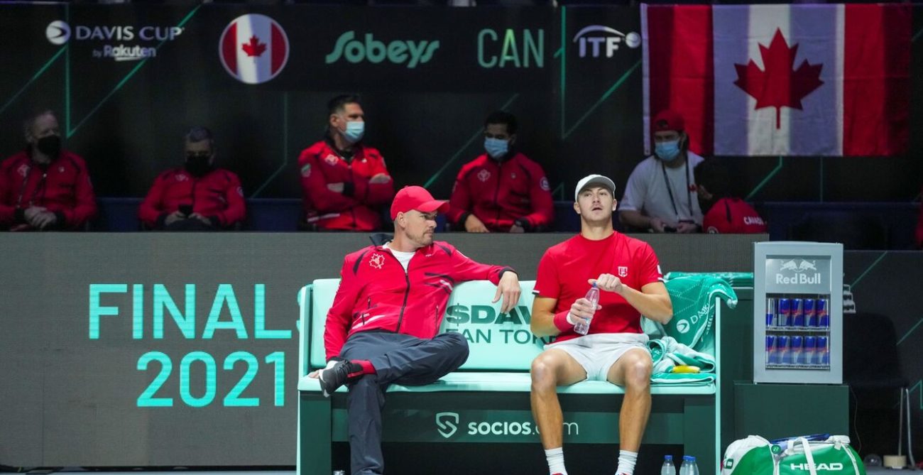 Frank Dancevic sits on the bench and talks to Brayden Schnur.