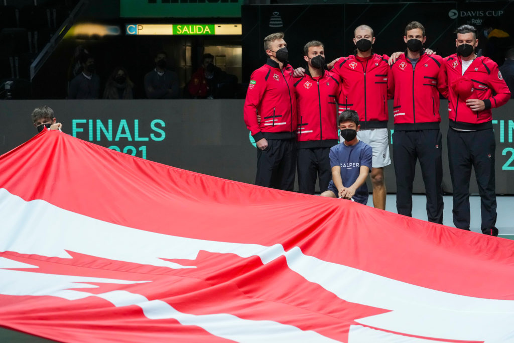 Davis Cup Canadian team in front of the Canadian flag held by ball kids