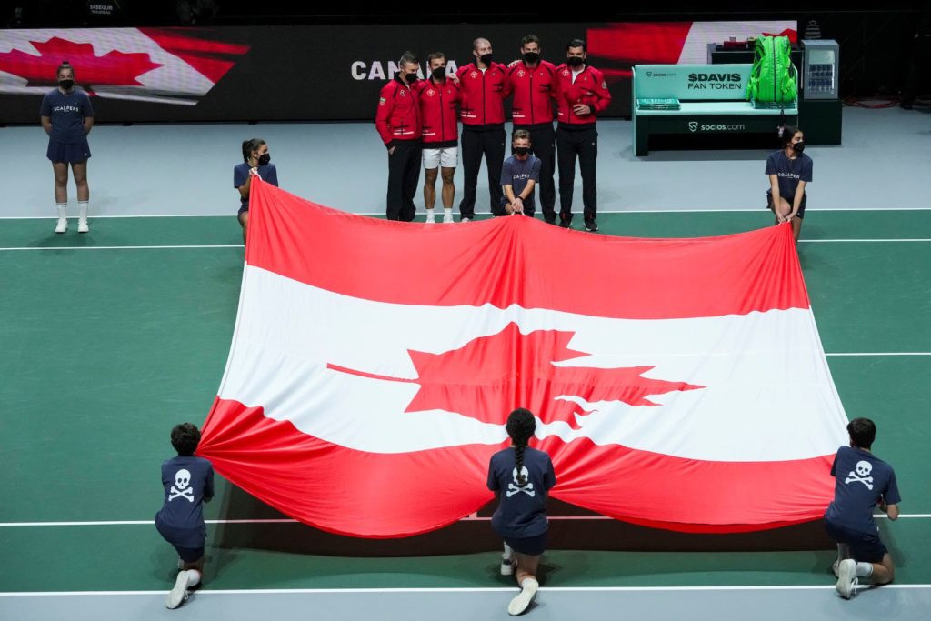 Team Canada at davis cup in front of a giant Canada flag held by ball kids before a tie starts