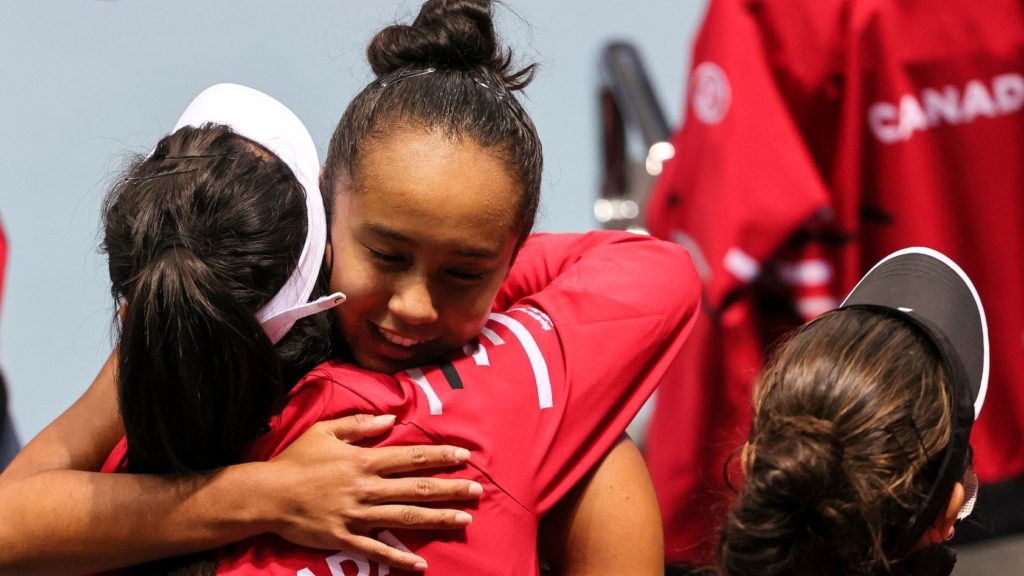 Leylah Fernandez hugs a person wearing a red jacket with Cnada written on it after a Billie Jean King Cup match