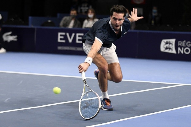 Tennis Player hits a low backhand slice indoors