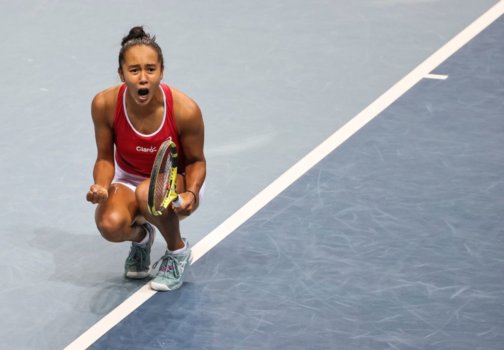 Leylah Fernandez crouches on court an yells after a win