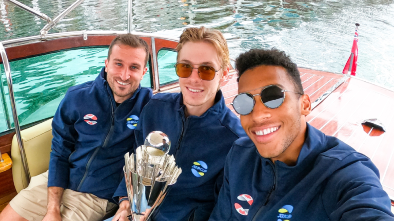 Steven Diez, Denis Shapovalov holding the ATP Cup trophy, and Felix Auger-Aliassime sit on a boat.