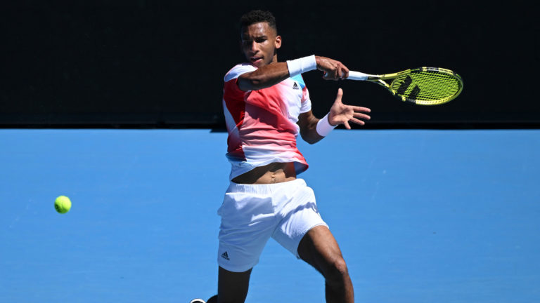 Auger-Aliassime leaps into the air as he follows through on a forehand.