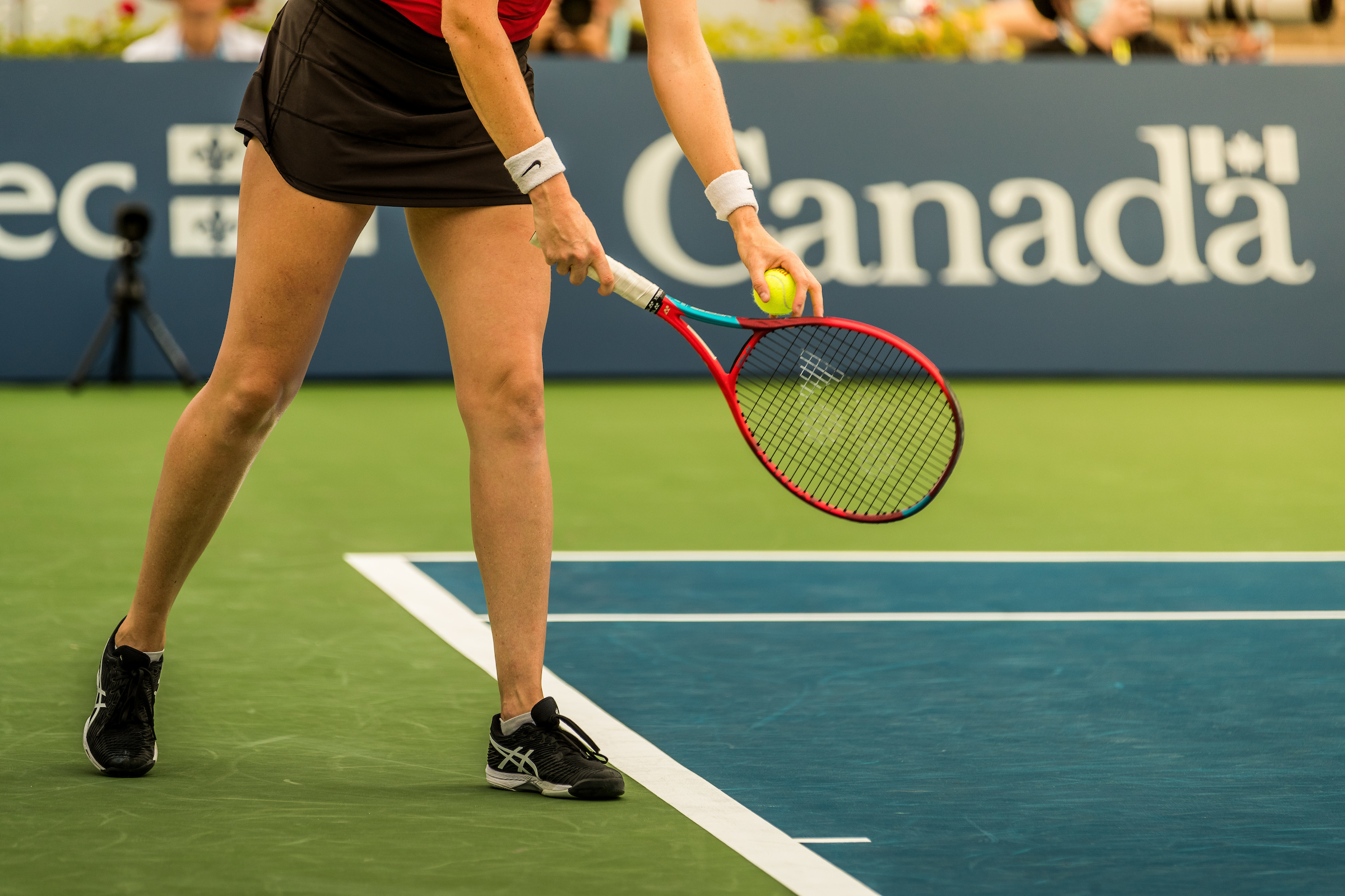 tennis player ready to serve, viewed from waist down