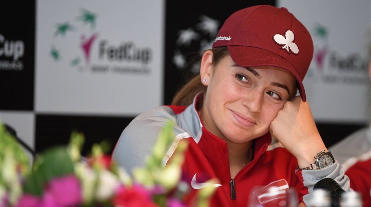 Jelena Ostapenko leans on her hand and smiles.