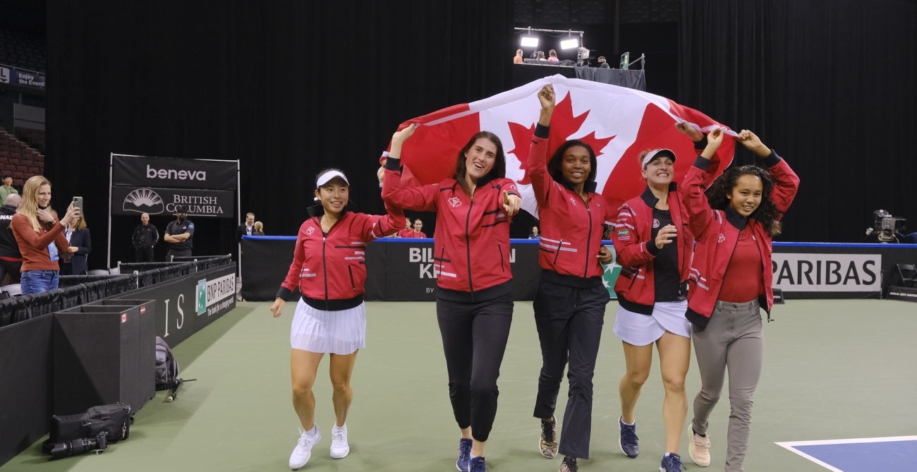 Carol Zhao, Rebecca Marino, Francoise Abanda, Gabriela Dabrowski and Leylah Fernandez walk around the court with the Canadian flag above their heads.