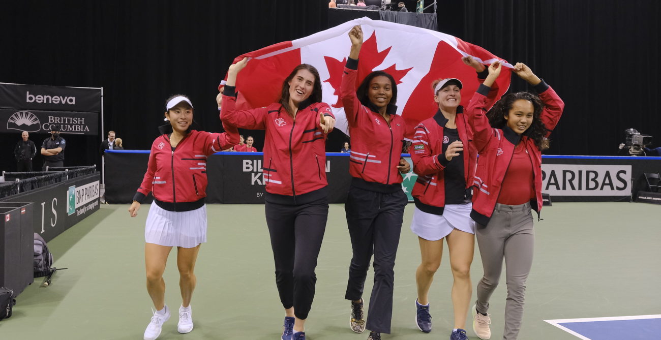 Carol Zhao, Rebecca Marino, Francoise Abanda, Gabriela Dabrowski and Leylah Fernandez walk around the court with the Canadian flag above their heads.