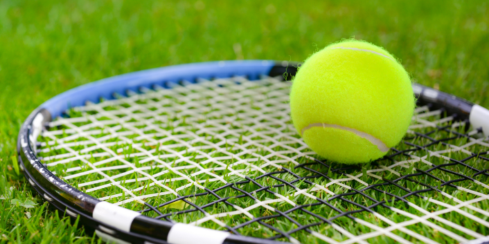 Tennis ball and racket on grass