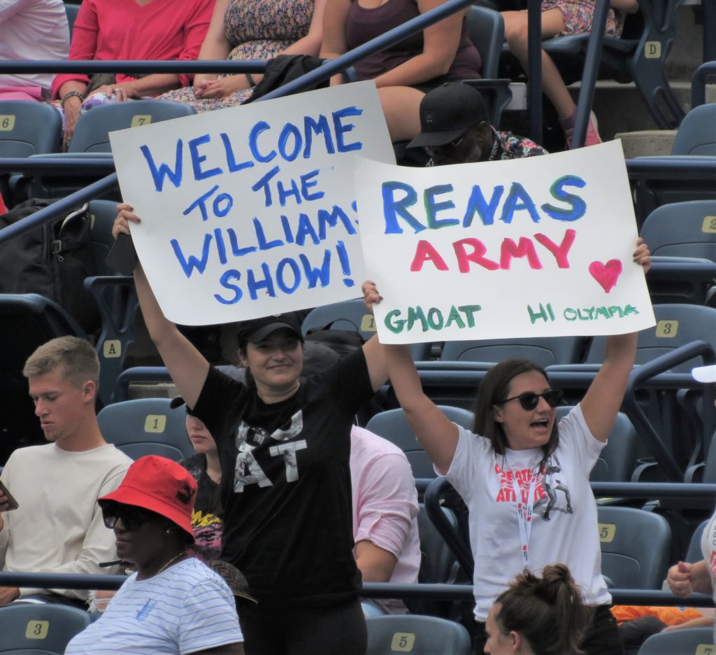 Several fans hold up signs supporting Serena Williams.