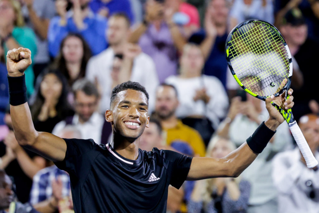 Felix Auger-Aliassime raises his hands in victory.