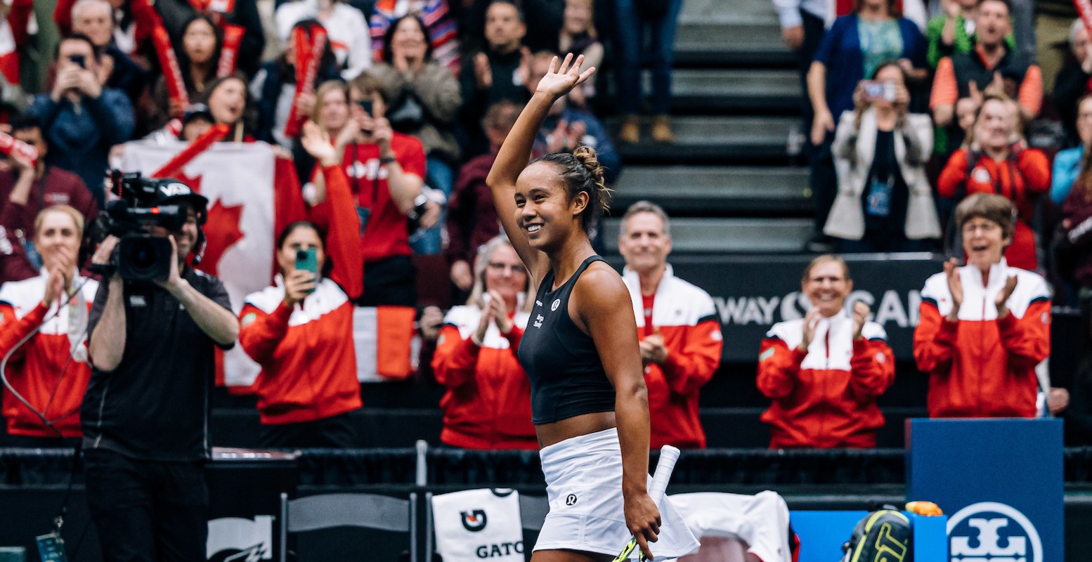 Leylah Fernandez waves to the crowd as Team Canada celebrates behind her.