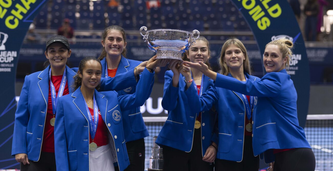From left to right: Heidi El Tabakh, Leylah Fernandez, Rebecca Marino, Marina Stakusic, Eugenie Bouchard, and Gabriela Dabrowski hold up the Billie Jean King Cup trophy while wearing their blue blazers.