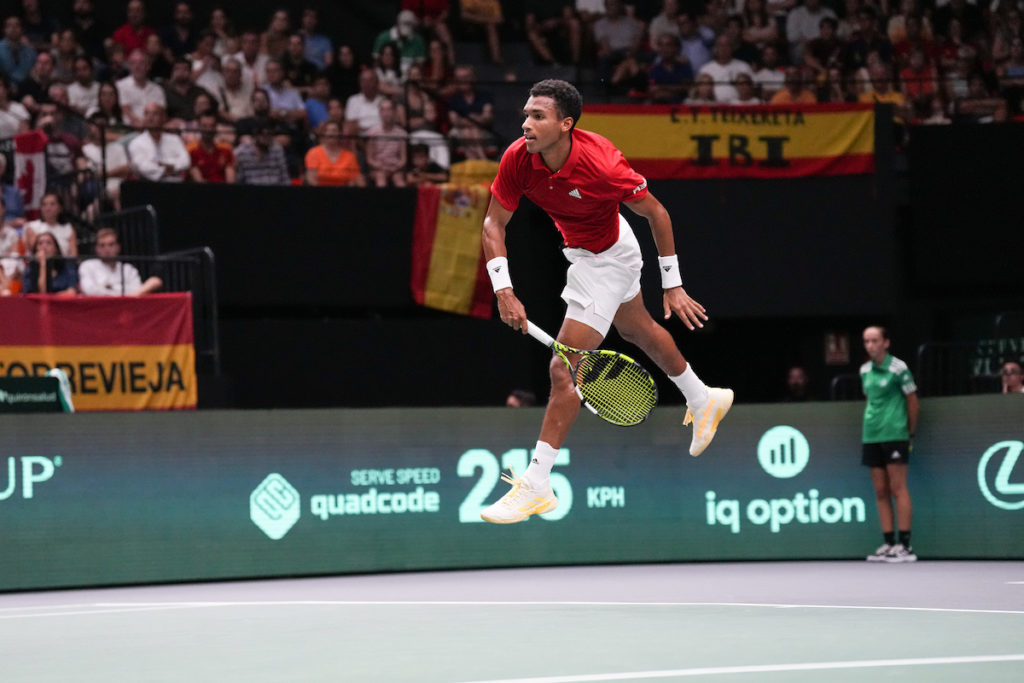 Felix Auger-Aliassime leaps into the air while serving