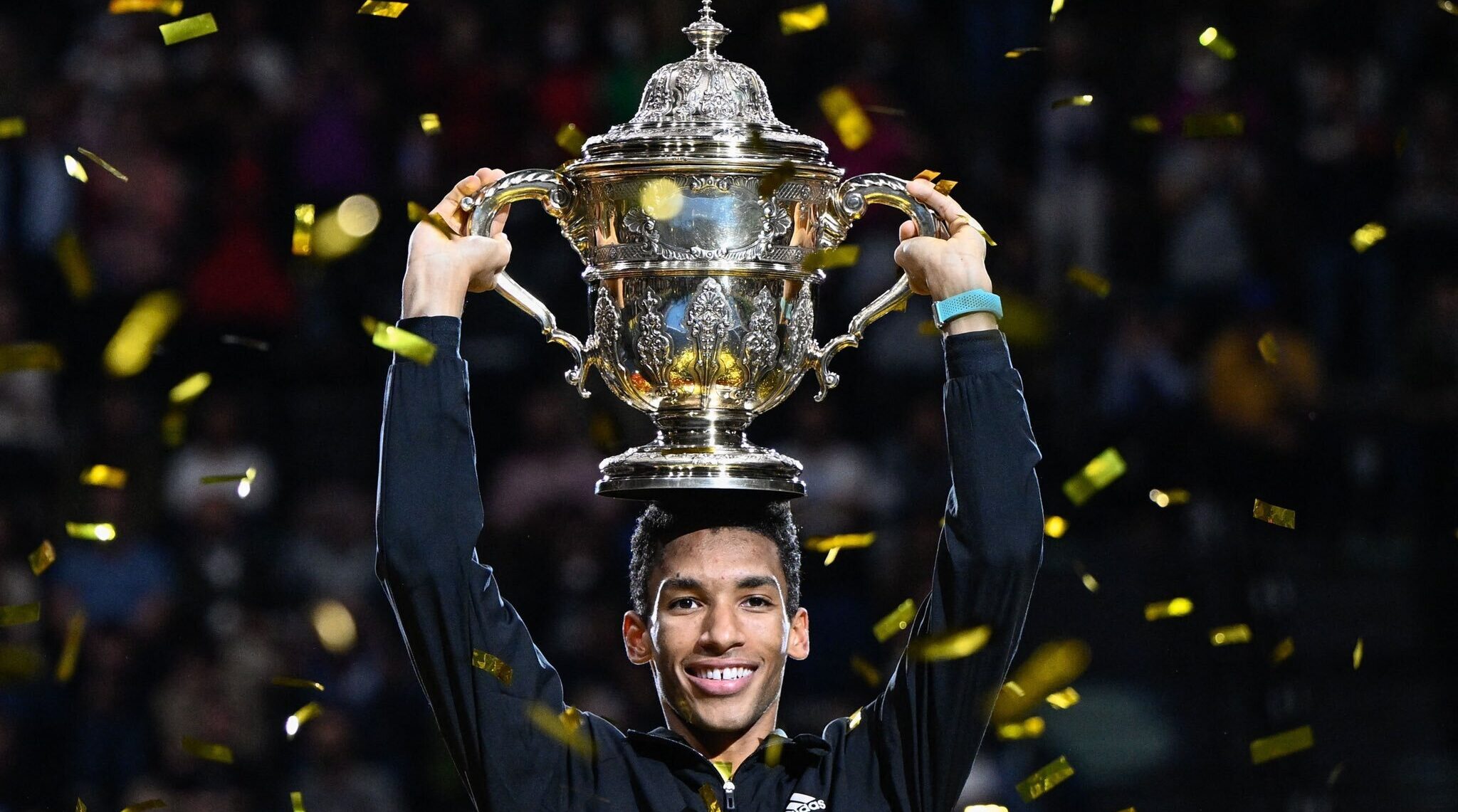 Felix Auger-Aliassime holds the Basel trophy above his head.