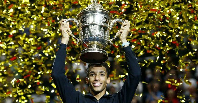 Felix Auger-Aliassime holds the basel trophy over his head.