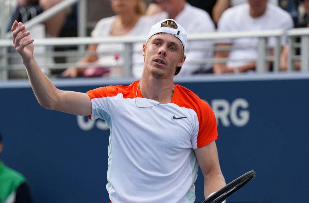 Denis Shapovalov raises a hand in the air to express frustration.
